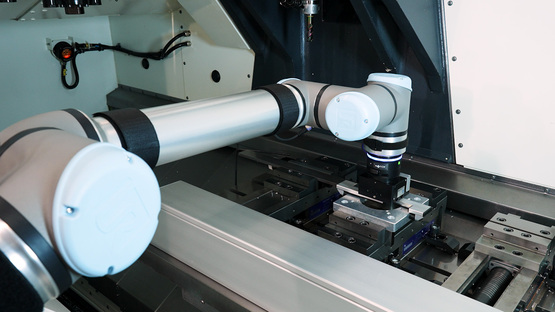 Cobot entnimmt einen Rohling aus einer Maschine